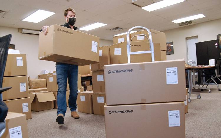Justin Sharpe, associate director of the Student Wellness Center, loads boxes of face masks destined for the Fuqua School of Business. Photo by Stephen Schramm.