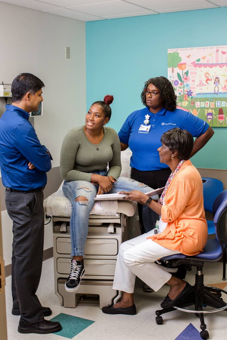 From left to right, hematologist Nirmish Shah, patient Reanna Daye, Reanna’s mother Stacie Daye, and Child and Adolescent Life Specialist Vivian Lewis discuss Reanna’s management of her sickle cell disease.