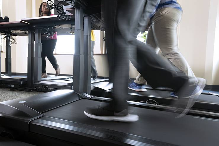 A member of the School of Nursing’s information technology department walks on a treadmill during a meeting.
