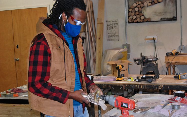 Hayes' studio on campus is a place where he can teach and work on his own projects, like this one smoothing the edges on a bronze hand for a sculpture. Photo by Jack Frederick. 