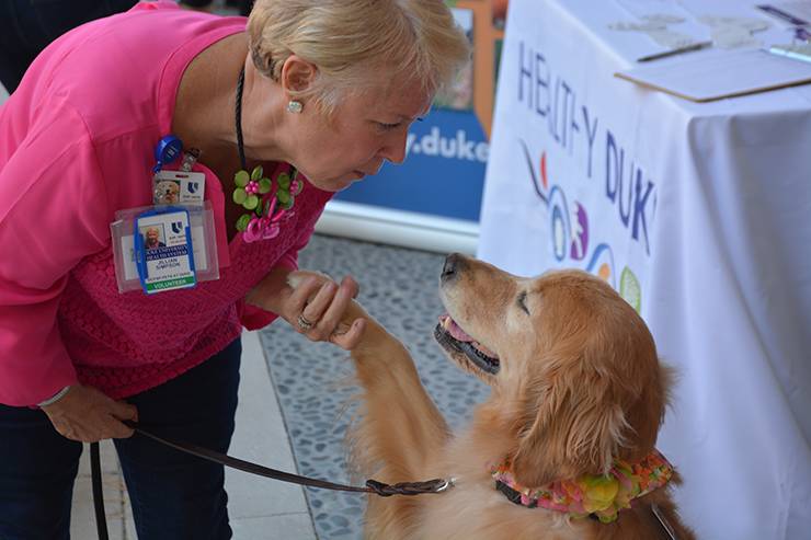 Jill Simpson shakes the hand of Riley, a therapy dog with the Pets at Duke program.