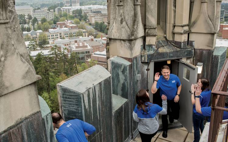 Brooke Povich, left, and Leslie Douglas, right, give high fives to Nathan McKinnis at the top of Duke University Chapel. 
