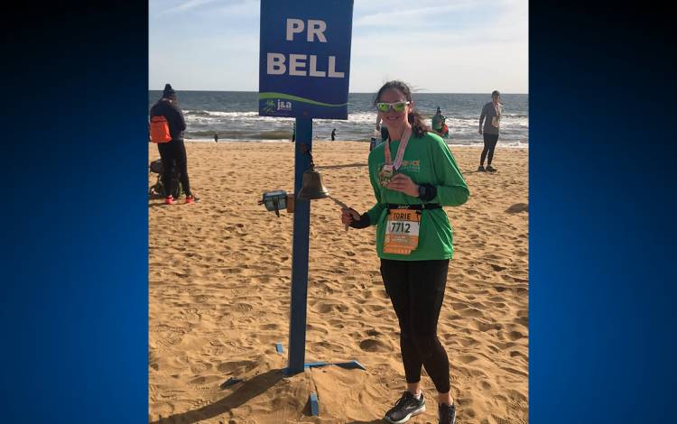 Torie Smith rings the bell for a personal best time at the Shamrock Half Marathon at Virginia Beach. Submitted photo.