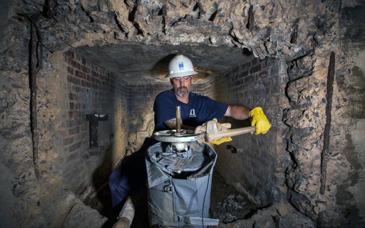 Tim Duggan uses a wrench to close a gate valve that carries the flow of steam.