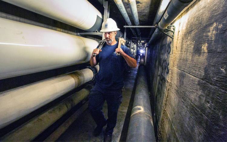 Tim Duggan carries wrenches through a long passageway in the tunnel.
