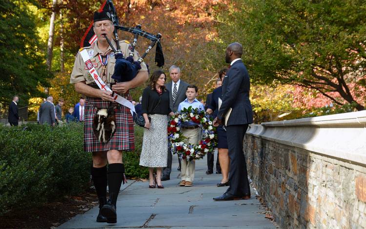 James Chambers plays the bagpipes while leading the family of Maj. Agustin Gonzalez to the Alumni Memorial Wall. Photo by Stephen Schramm.