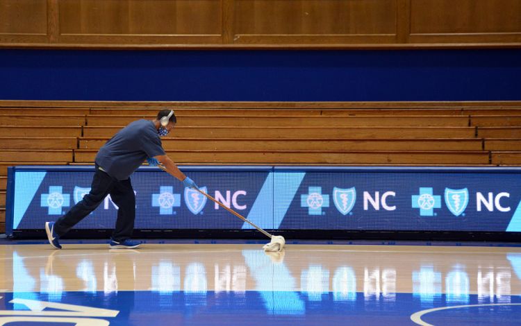 University Environmental Services Utility Worker William Harris makes the Cameron Indoor Stadium court shine prior to warm-ups. Photo by Stephen Schramm.