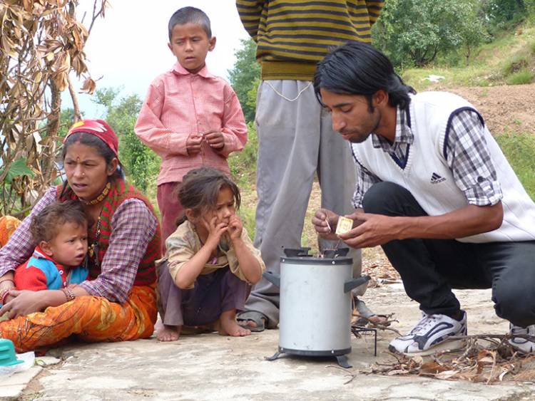 A family in rural India watches as a salesman demonstrates a new cookstove