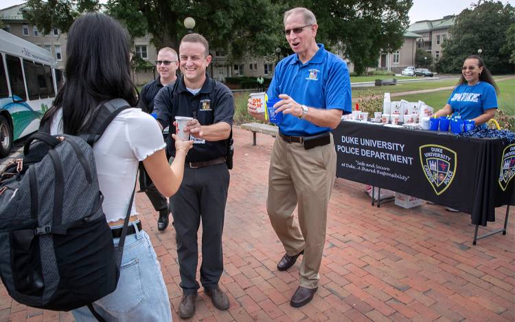 Kelly George, center, and Eric Hester, right, hand out coffee and donuts to students on East Campus.