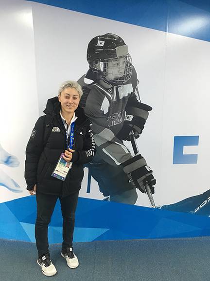 Duke Olympian Randi Griffin poses at the Team Korea House inside Gangneung Olympic Park in front of a poster of one of her teammates, Danelle Im. Photo courtesy of the Korean Ice Hockey Association.