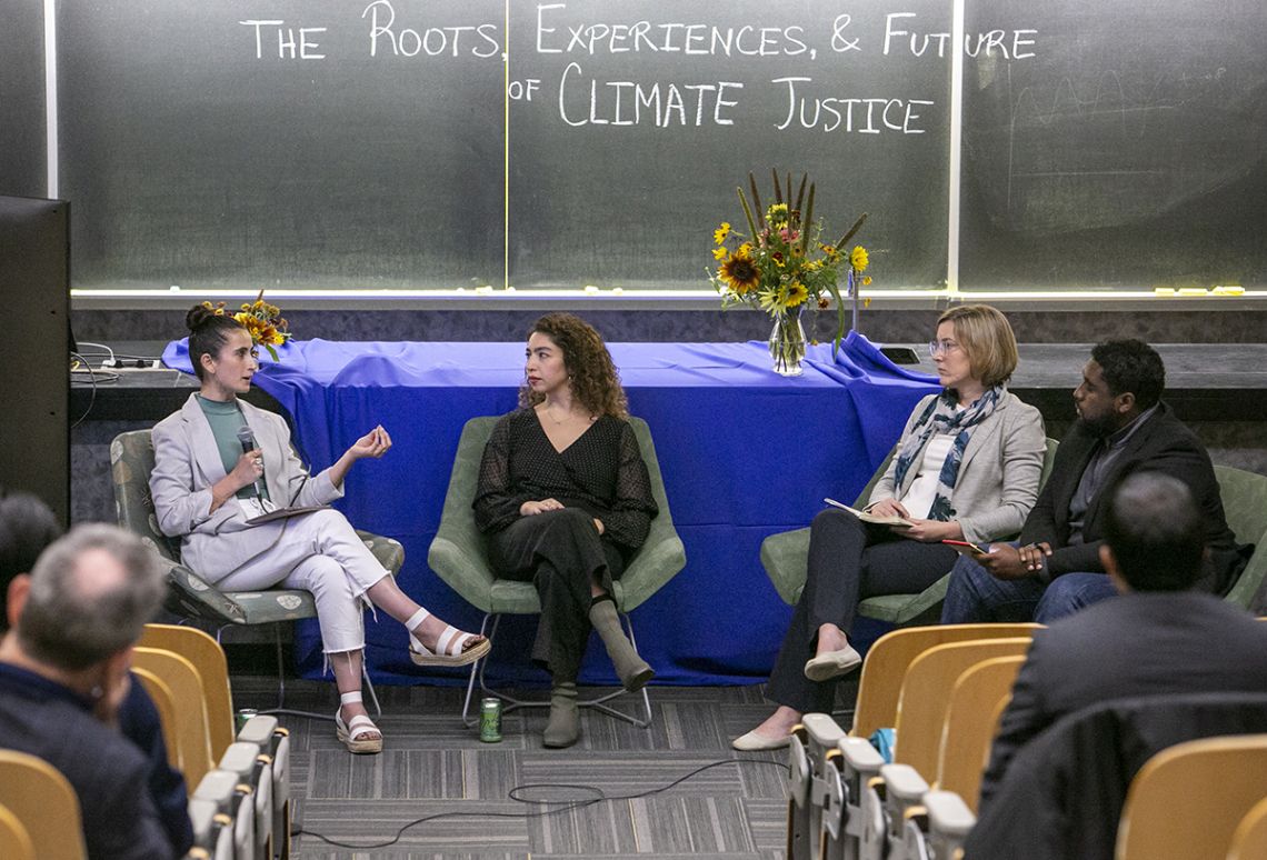 A seated group of individuals in front of a chalkboard that reads,