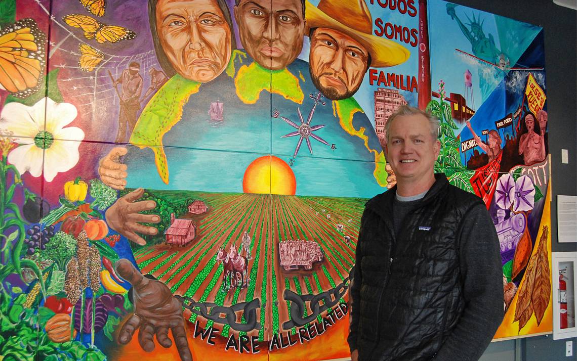 Bill Fick stands in front of the Rubenstein Arts Center's mural created by Duke students and Durham artist Cornelio Campos. Photo by Stephen Schramm.