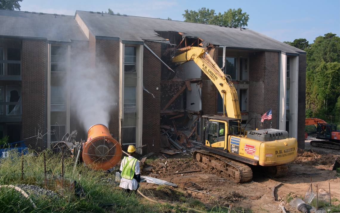 Water sprays onto a former Central Campus apartment to reduce dust during building removal. Crews began demolishing buildings on Central Campus during the morning of Aug. 13. Photo by Jonathan Black.