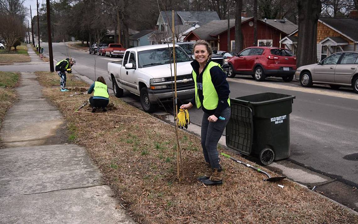 Duke Hospital nurse Ali Homan smiles as she plants trees in Durham's Walltown neighborhood.