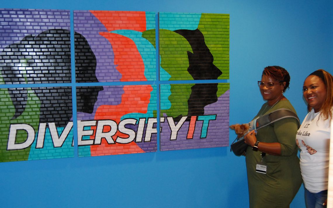 Attendees Trina Rodriguez, left, and La’Shawnda Kendall pose in front of the DiversifyIT art piece called A Work In Progress on Aug. 29. Photo by Jack Frederick