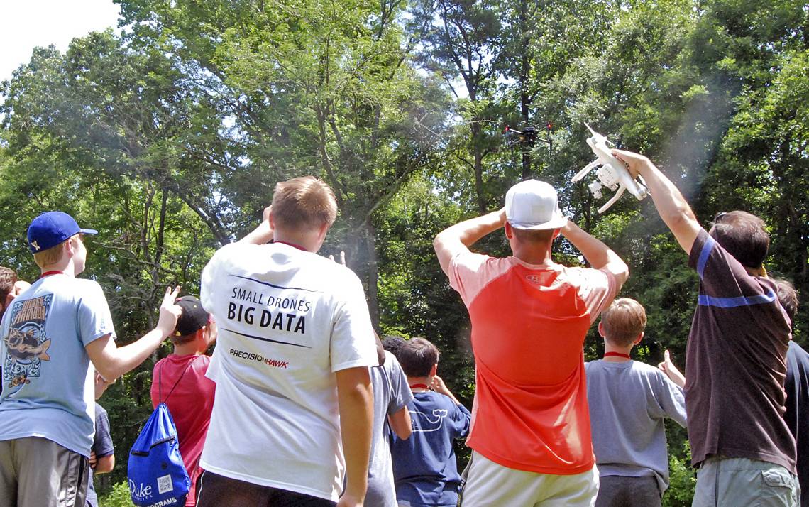 Kids watch a drone fly in Duke Forest.