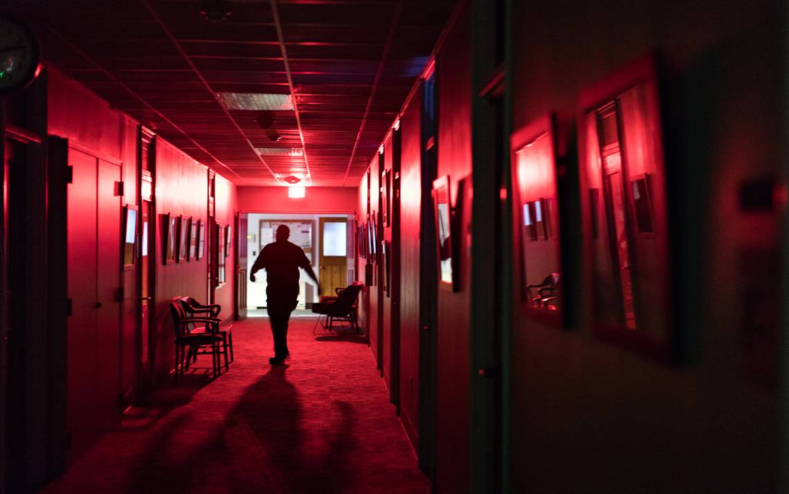 Roosevelt Hall, a general maintenance mechanic with Duke Facilities Management, checks on light fixture in the Allen Building during one of his night shifts.