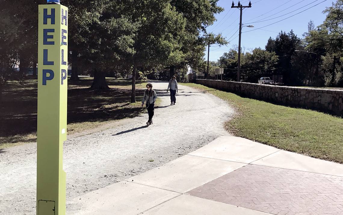 A blue emergency phone shown amid a campus scene.