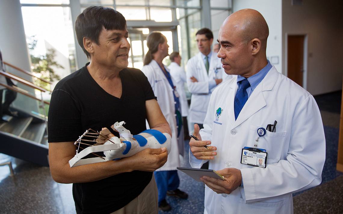 Duke Medical Interpreter Joel Pena, right, talks with hand transplant patient Rene Chavez. Photo by Shawn Rocco, Duke Health.