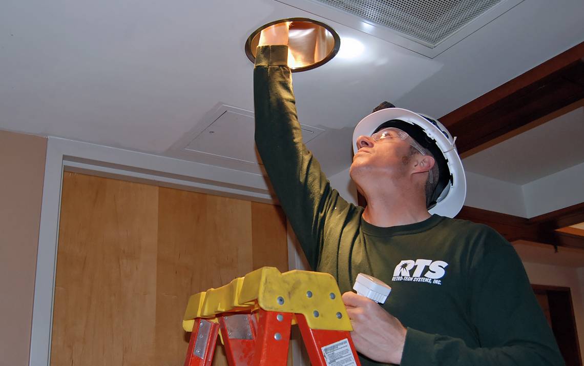 Installer Ryan Roberson puts LED lights into fixtures in Sanford Hall.