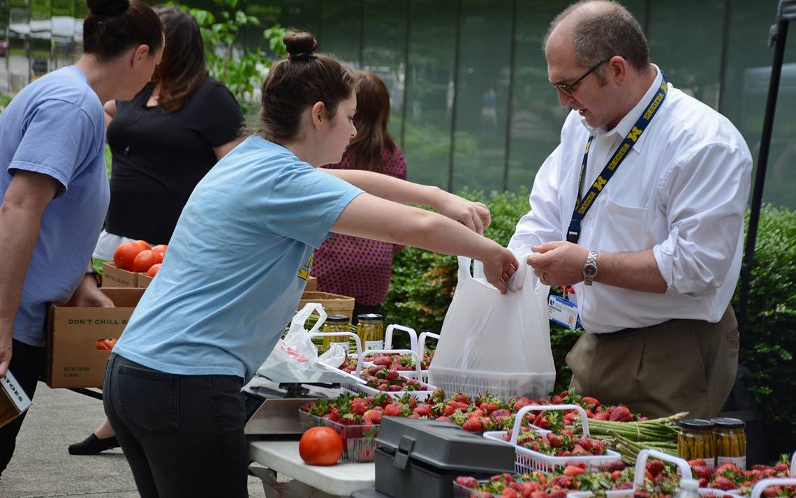 Eric Lipp, far right, buys strawberries from the Lyon Farms stand at the Duke Farmers Market. Photos by Jonathan Black.