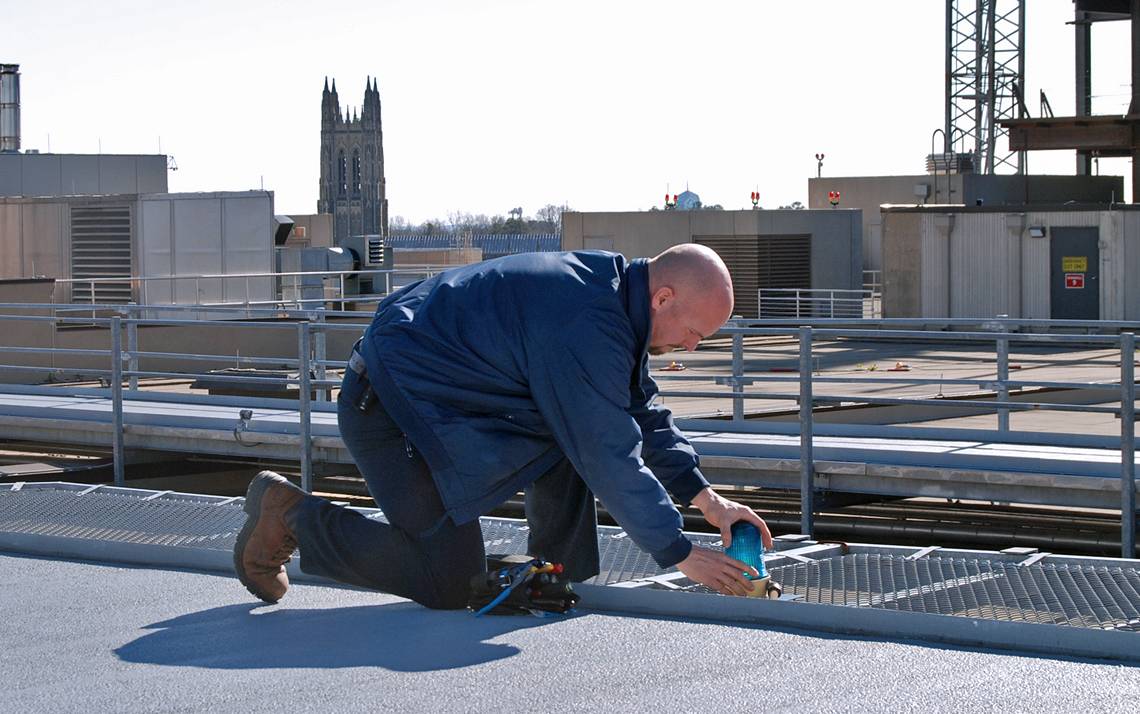Electrician Bob Moffett repairs a light on top of Duke University Hospital. Photo by Stephen Schramm.