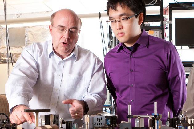 Duke Professor Warren Warren coaches a student in a laser lab