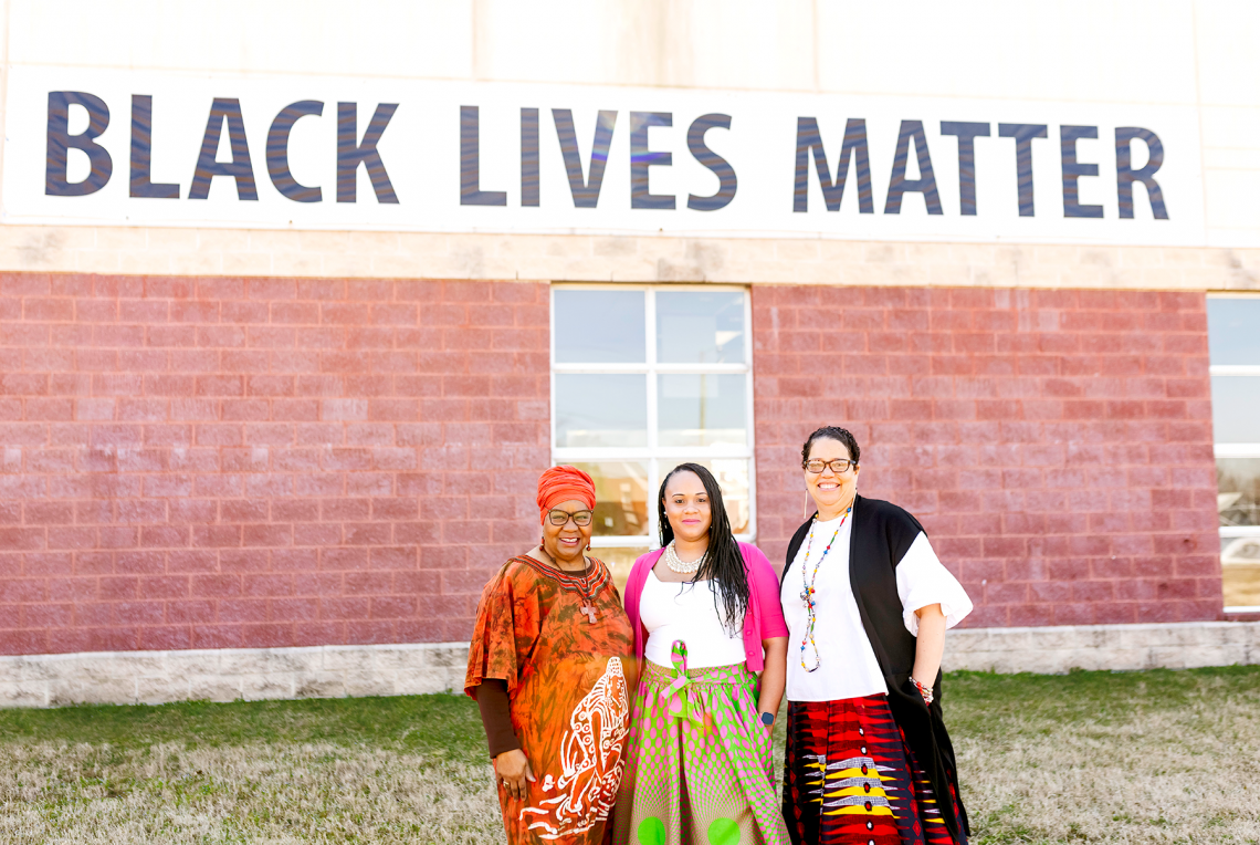 Photo of three black women pastors in front of Black Lives Matter mural