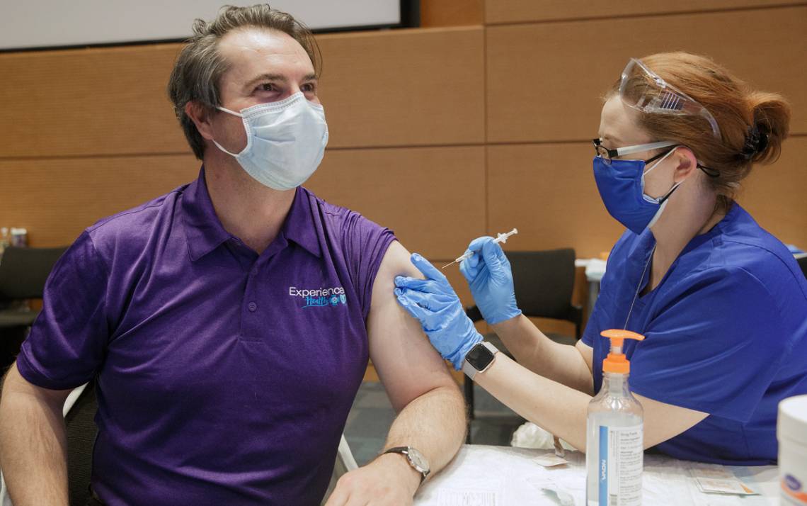 John Yeatts, an internal medicine doctor, left, gets his COVID-19 vaccine from Crystal Adams, a nursing informatics systems specialist at Duke. Photo by Shawn Rocco.