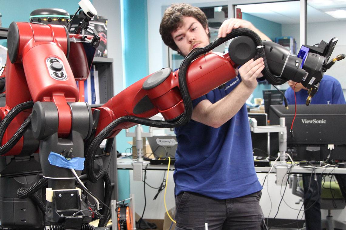 A student works on a robot arm