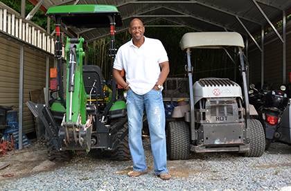 Albert Rogers Jr. stands in front of a few pieces of grounds equipment next to his Central Campus office, including a John Deere tractor he and his team have named “Betsy.” They have come up with fun names for many pieces of Central Campus equipment,