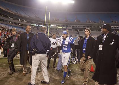 Chris Cook, second from right, leads Duke wide receiver Connor Vernon off the field after the 2012 Belk Bowl. Cook and his colleagues in Duke Athletics were recently recognized as one of the 11 best sports information departments for football by the Foot