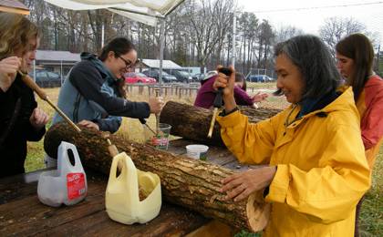 Jo-C Gaston, right, a nurse with Duke's LIVE FOR LIFE employee wellness program, helps inoculate logs at a Duke Campus Farm workshop. Photo courtesy of Emily Sloss.