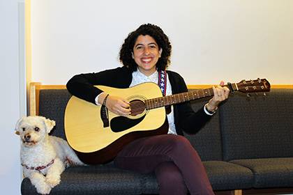 Elana Friedman poses with a guitar she keeps in her office. She's joined by her dog, Barley. Photo courtesy of Elana Friedman.