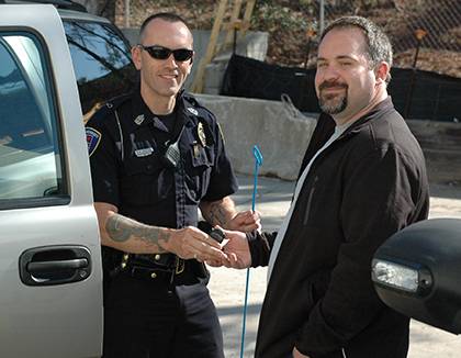 Duke lab assistant Shawn Johnson, right, serves as a Facility Watch coordinator for his building, Medical Sciences Research Building II, and is an alumnus of the Duke Police Citizens' Police Academy. In this photo, he poses as a locked-out motorist recei