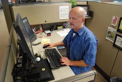 Michael Palko, a Maestro Care principal trainer with Duke's Health System, performs his desk work while standing up. Photo by Bryan Roth.