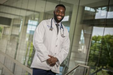 posed photograph of medical school graduate in white doctor's coat