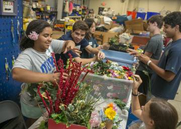 Students with Project BUILD help sort artificial flowers, toys and other items at The Scrap Exchange