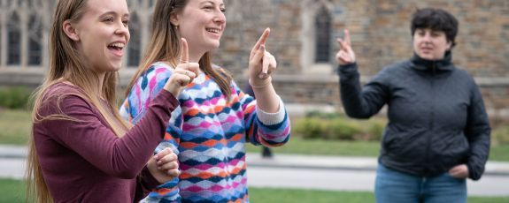 Lily Elman (sweater) and Emma Runia (maroon shirt) lead a “Signing 101 Teach-in” on Abele Quad as part of ASL Awareness days. Photo by Bill Snead