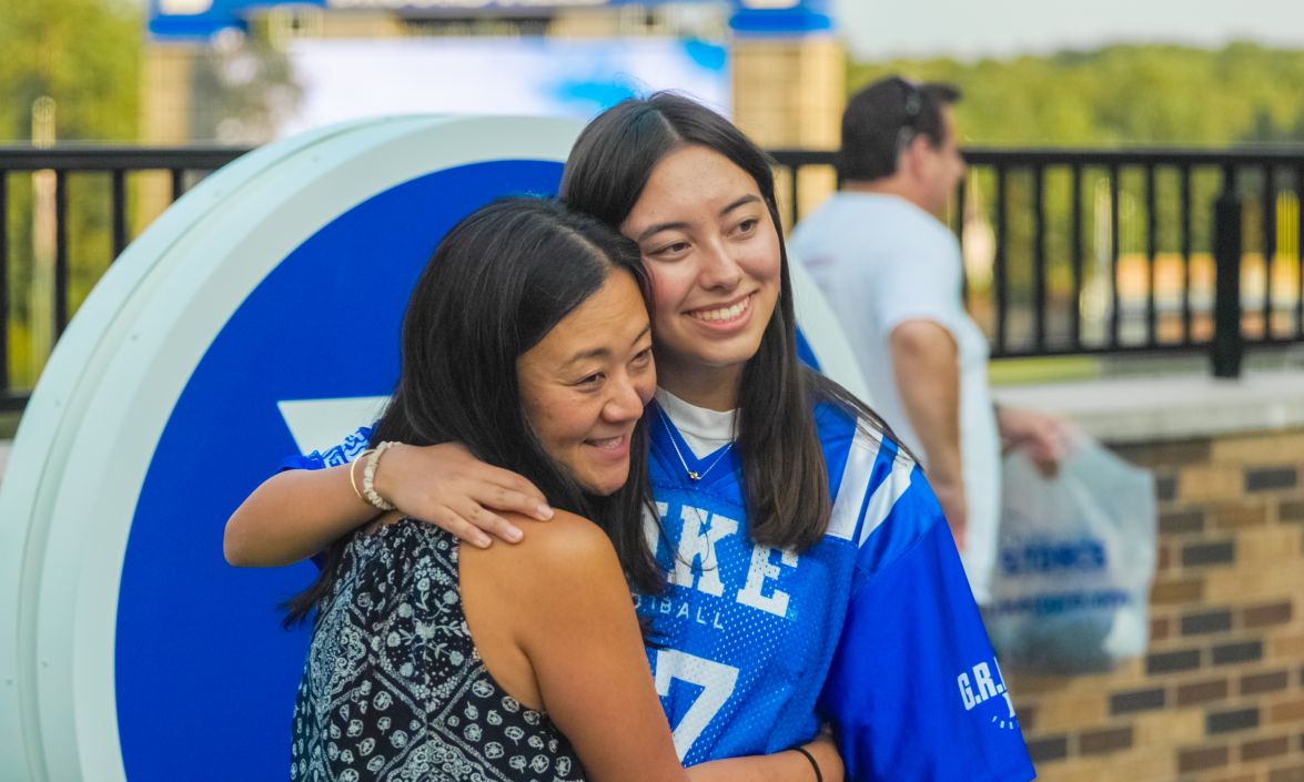 Two people hug and take a photo outside near Wallace Wade Stadium as families say farewell