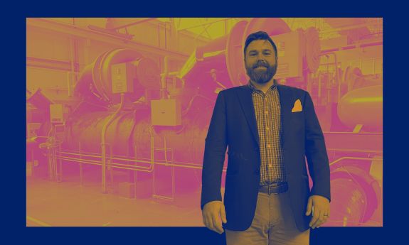 Casey Collins standing in chilled water plant with Climate Commitment branded colors