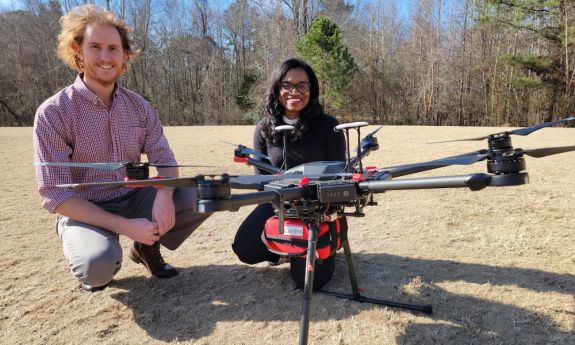 Cardiologist Dr. Monique Starks and drone pilot Evan Arnold, research associate at the Institute for Transportation Research and Education at NC State, take a drone out for a test flight. The AED is attached in the red box underneath the drone. Credit: Elizabeth Switzer, Duke Department of Medicine. 