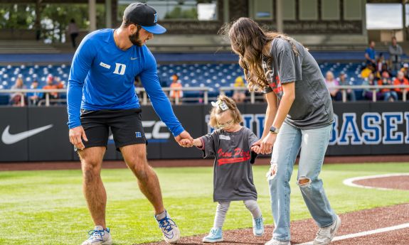 duke baseball player helps young girl run the bases at Coombs Stadium