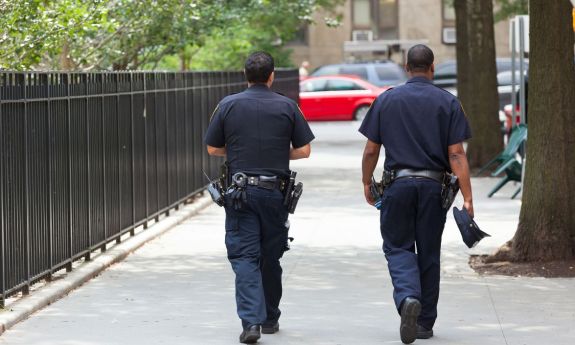 two police officers walking down a sidewalk