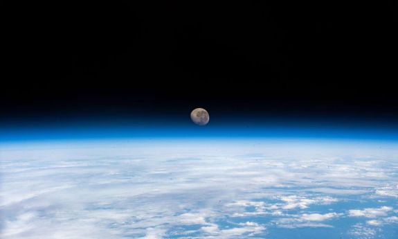 photo from space of the moon rising above the earth