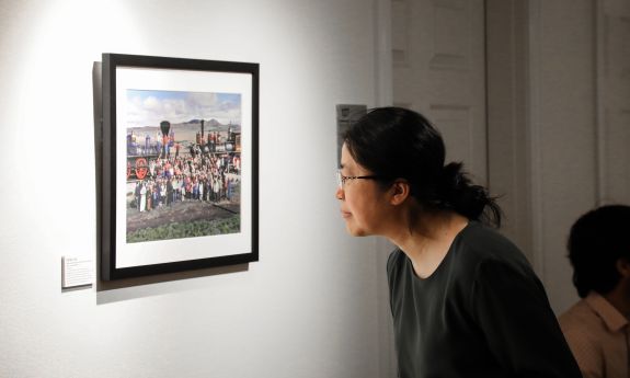 Person viewing a photograph of a railroad by photographer Corky Lee.