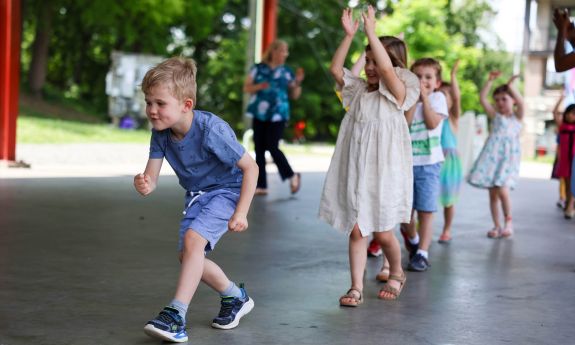 Duke Children's Campus students as they walk into their graduation celebration clapping to music.