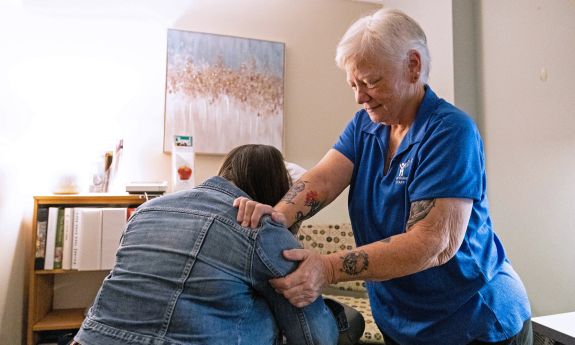 A massage therapist performs a chair massage on a client