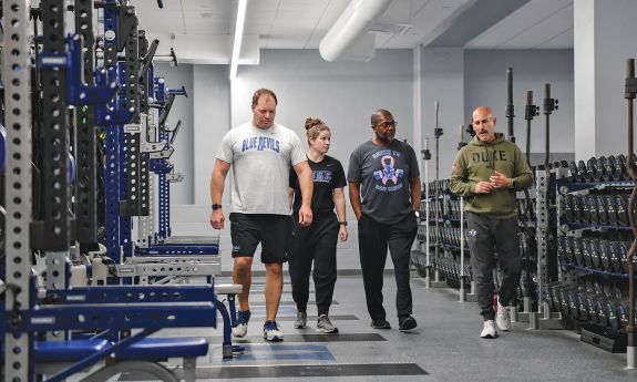 Four people in a weight room