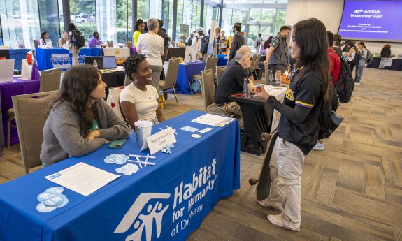 Student at the volunteer fair talking to people at a Habitat for humanities table